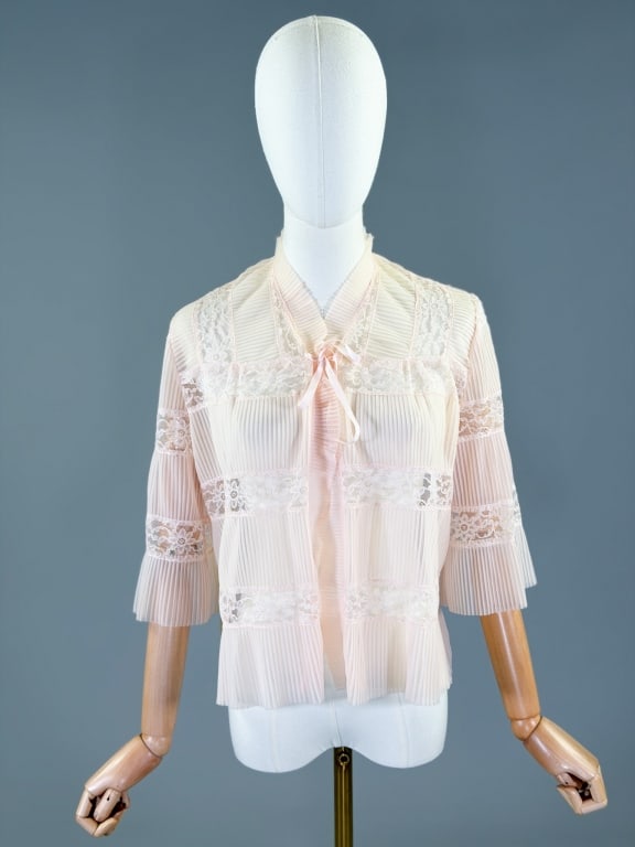 Vintage 1950s Pleated Nylon Lace Bed Jacket: Vintage 1950s Pleated Nylon Lace Bed Jacket having pleating throughout with lace inset details, closing at front with tie. Measuring free bust, 21 inches long, 15 inch sleeve length. General wear as s