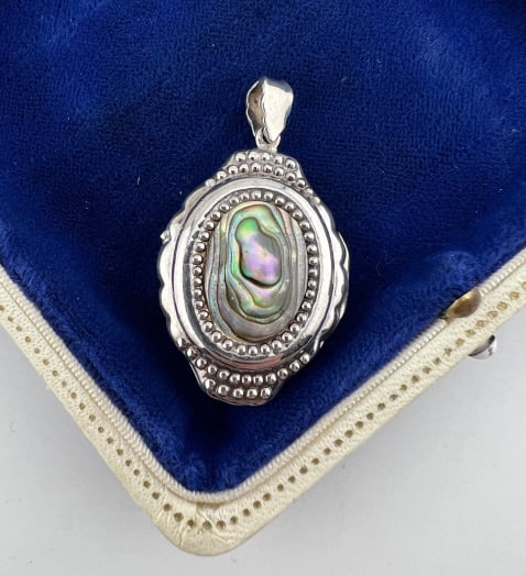 Sterling Silver & Abalone Shell Locket Pendant: Sterling Silver & Abalone Shell Locket Pendant. Art Deco style, sterling silver, hallmarked interior, each side set with oval plaque of abalone shell. Measures 1.75 inches in length.
