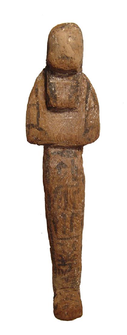 An Egyptian wood ushabti, Late New Kingdom: An Egyptian wood ushabti, Late New Kingdom, c. 1200 - 1075 BC, mummiform, wearing tripartite wig, arms folded at chest, hands holding hoes, bag at center of back and vertical column of hieroglyphic te