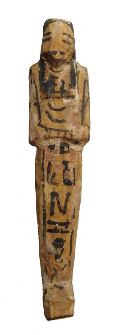 An Egyptian painted wood ushabti, Late New Kingdom: An Egyptian painted wood ushabti, Late New Kingdom, c. 1200 - 1075 BC, mummiform, wearing tripartite wig, arms crossed at mid-section, each hand holding a hoe, basket on back. The details are painted 