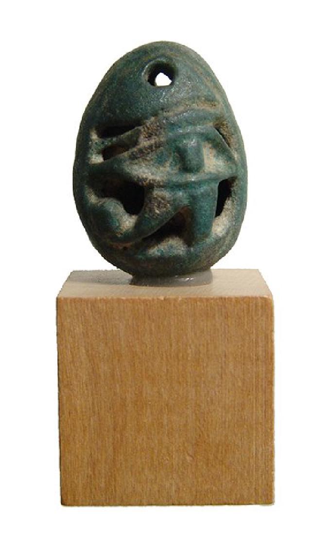 Egyptian faience bead with central Eye of Horus: An Egyptian faience bead with central Eye of Horus, 3rd Intermediate Period, c. 1075 - 712 BC, of attractive open-work style, the Wedjat nicely detailed with well-preserved green color. 23 x 17 mm. Mo