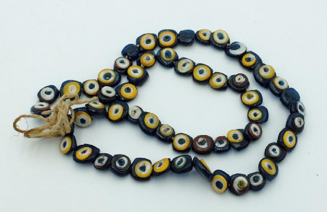 A nice strand of antique Islamic 'eye' beads, 1800's: A nice strand of antique Islamic 'eye' beads, 1800's. The strand is 20 in long and is comprised of dark blue beads with most of the 'eyes' formed in yellow and white, with blue centers. Ex Liebert est