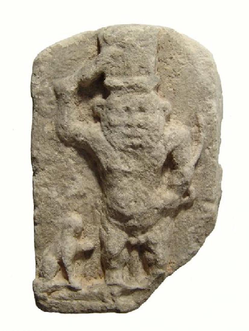An Egyptian limestone plaque depicting Bes, Late Period: An Egyptian limestone plaque depicting Bes, Late Period, c. 664 - 332 BC, the god, with tall feathered headdress, stands atop the backs of two crocodiles, holding a sword above his head with his right