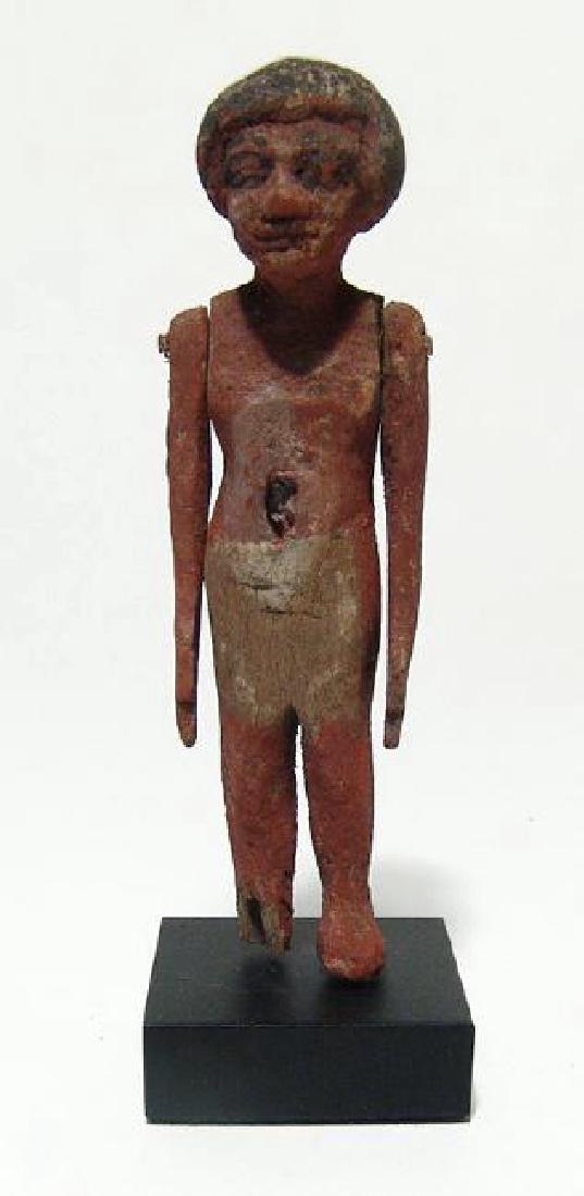 Egyptian wood painted figure of a man, Middle Kingdom: An Egyptian wood painted figure of a man, Middle Kingdom, c. 2061 - 1690 BC, wearing short kilt and short wig, his hands pendant at his side. H: 4 in (10.3cm). Well-preserved with much original pigmen