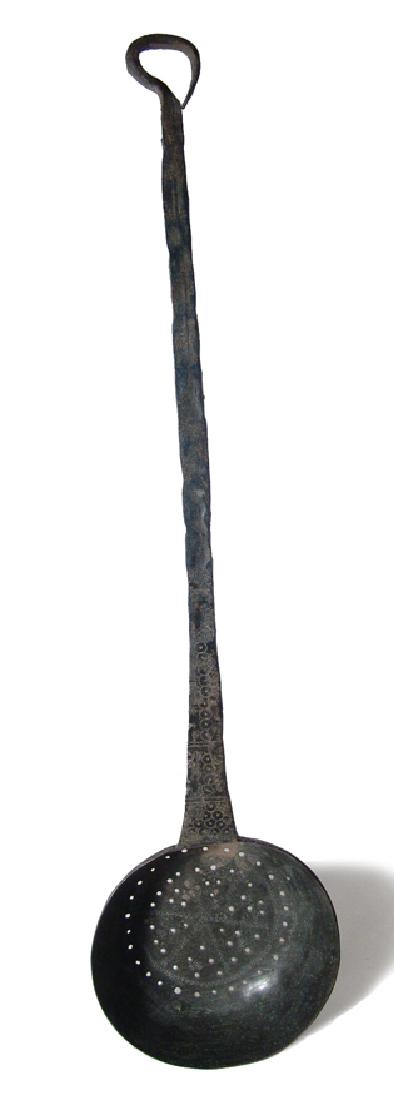 A large bronze strainer with long handle, Byzantine: A large bronze strainer with long handle, Byzantine, c. 6th - 8th Century AD, hammered from a single piece of metal. The bowl is punched with holes for draining and nicely incised with a central flowe