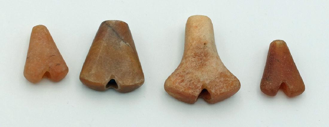 A group of 4 Tairona 'anchor' pendants from Colombia: A group of 4 Tairona 'anchor' pendants from Colombia, ca. AD 1000 – 1500. They are made from translucent carnelian and range from ¾ in to 1 in in length. All are perforated lengthwise. Ex New World