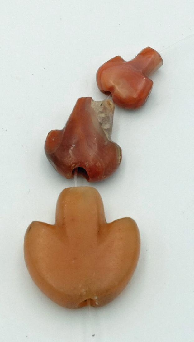 Trio of Tairona 'Anchor' type pendants from Colombia: A trio of Tairona 'Anchor' type pendants from Colombia, c. 1000 - 1500 AD. They are 7/8 in, 3/4 in and 1/2 in long and are made from highly polished carnelian. Ex New World Artifacts Gallery.