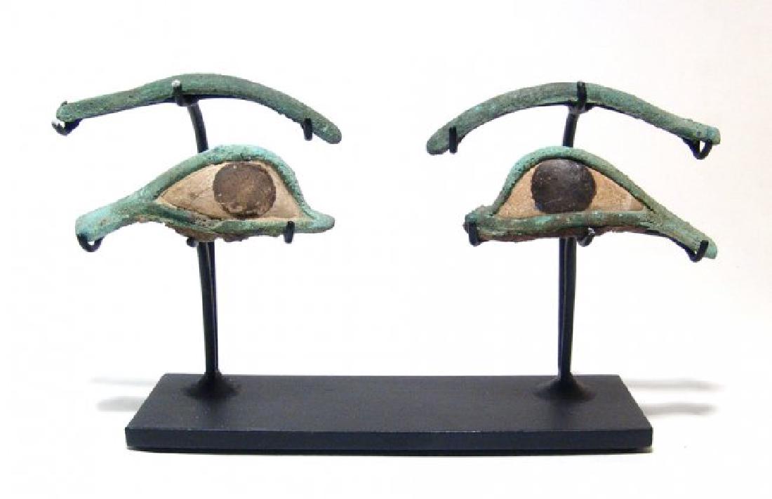 A pair of Egyptian bronze eye and brow inlays: A pair of Egyptian bronze eye and brow inlays, 3rd Intermediate - Late Period, c. 1075 - 343 BC, the lids extending with cosmetic lines, the interiors inlaid with limestone sclerae, the irises in blac