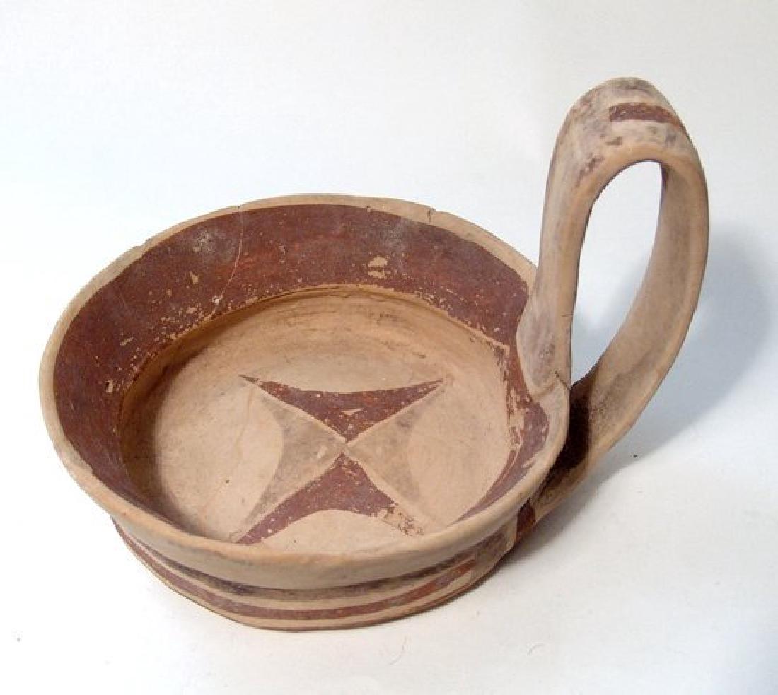 A nicely decorated Daunian kyathos, South Italy: A nicely decorated Daunian kyathos, South Italy, c. 5th Century BC, the bowl with central star device, bands around the outside and around the bottom, where they encircle a cruciform device. The tall 