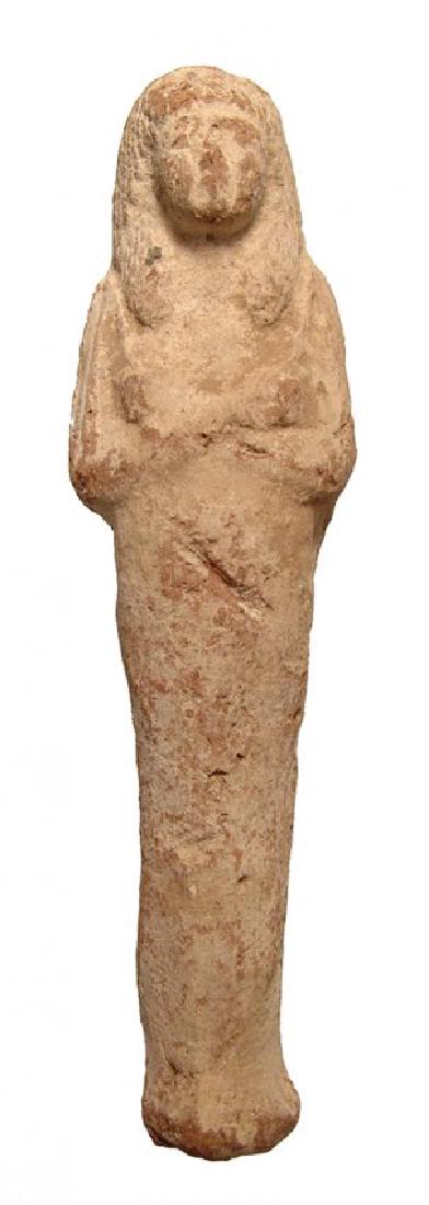 A large Egyptian terracotta ushabti, Late New Kingdom: A large Egyptian terracotta ushabti, Late New Kingdom, c. 1200 - 1075 BC, frontally molded and depicted mummiform, wearing layered wig, arms folded at chest, hands holding hoes. The features are attra