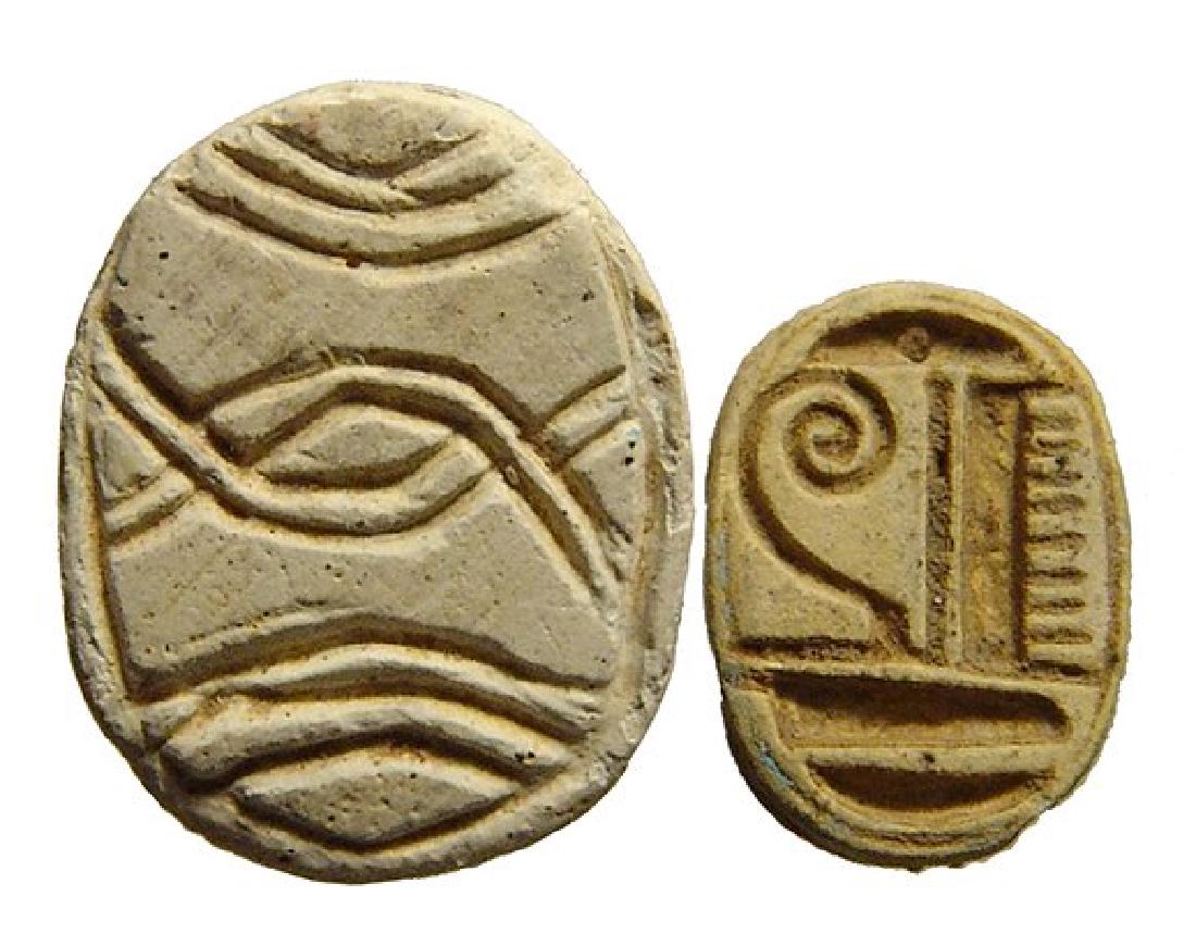 A lot of 2 Egyptian steatite scarabs: A lot of 2 Egyptian steatite scarabs. Lot includes a charming New Kingdom type, c. 1570 - 1075 BC, with well-carved body and the name of Amen-Re on the base, (12 x 8 mm), and the second a 2nd Intermed