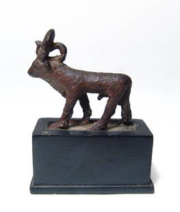 An Egyptian bronze Apis bull figurine, Late Period: An Egyptian bronze Apis bull figurine, Late Period, c. 664 - 332 BC, wearing solar disk and uraeus, suspension loop behind the neck, winged vulture over the rump. L: 1 in (4.5cm), H: 1 1/3 in