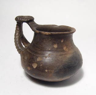 A wonderfully styled Villanovan impasto juglet: A wonderfully styled Villanovan impasto juglet, c. 8th Century BC, with intricate ribbed wishbone handle topped with a ribbed circle. H: 3 5/8 in (9.3 cm). Light deposits, minor surface weathering.