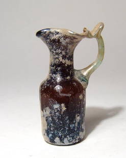 A beautiful Roman amber glass pitcher: A beautiful Roman amber glass pitcher, 4th - 5th Century AD, the cylindrical body with vertical indentation and indented base with pontil mark, the cylindrical neck with trefoil spout and applied