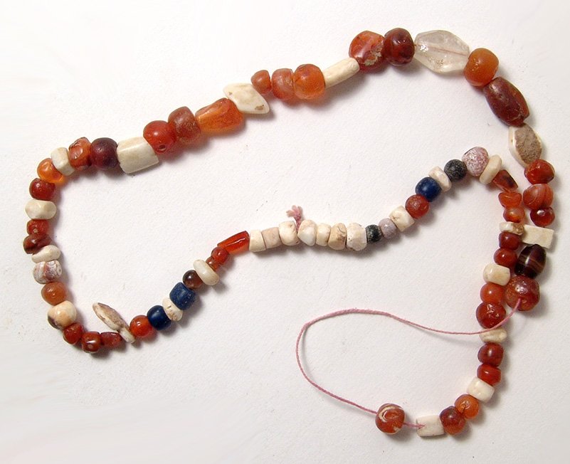 A strand of ancient carnelian beads: A strand of ancient carnelian beads, c. 1st Millennium BC, of various shapes and sizes and strung with a nice faceted quartz or 'rock crystal' bead and a few later Roman blue glass beads. Ex Malter Ga