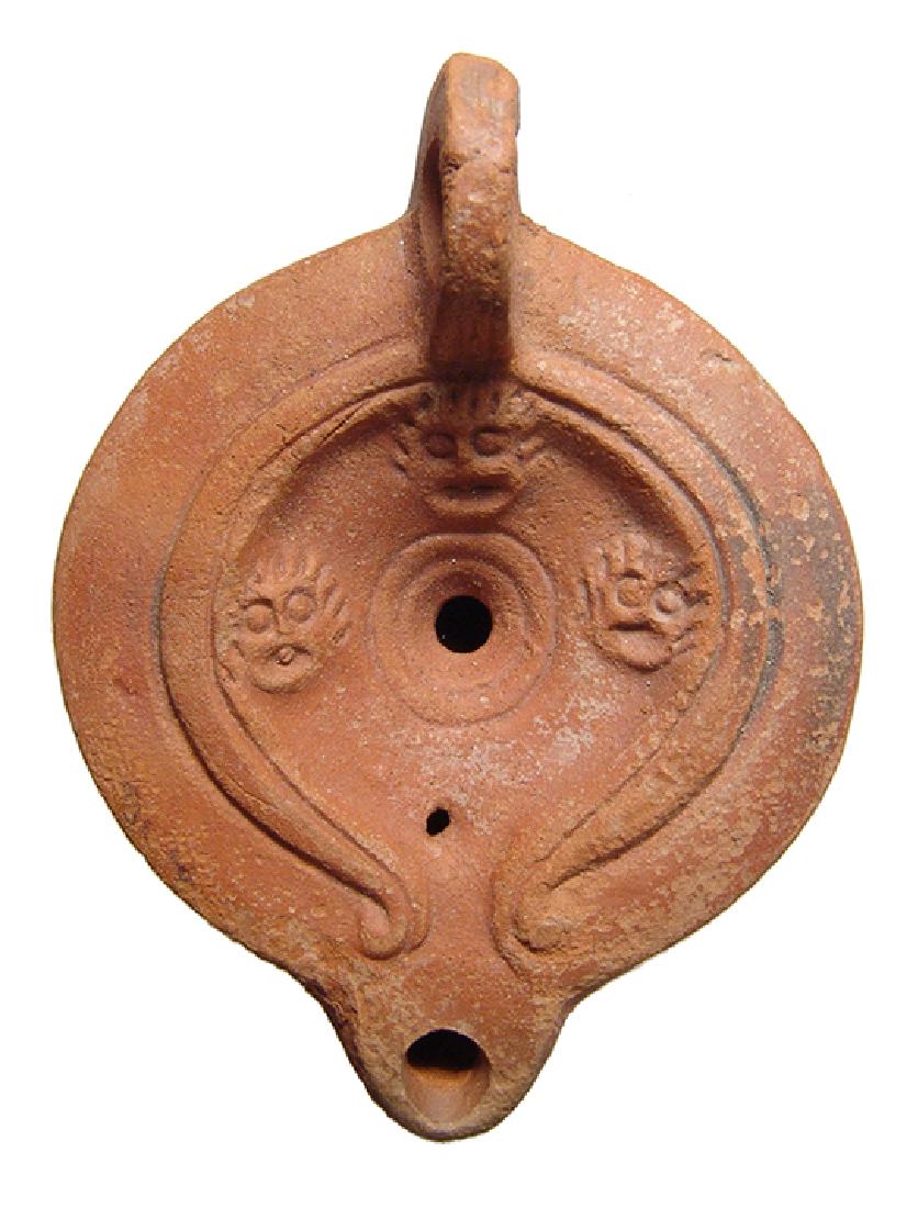 A Roman discus lamp with three theater masks (1 of 3)
