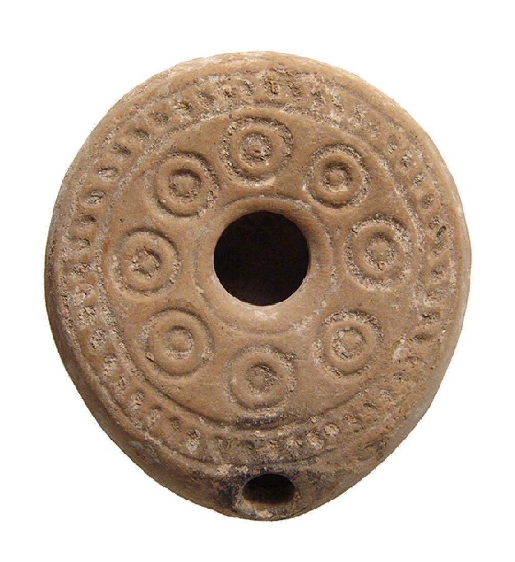 An attractive Byzantine circular lamp: An attractive Byzantine circular lamp, 5th - 7th Century AD, the top adorned with a band of circles and hatches around the fill hole, on base parallel lines bordered by divots running lengthwise, a ge