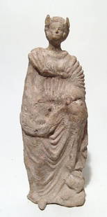 A late Hellenistic terracotta figure of a robed woman: A late Hellenistic terracotta figure of a robed woman, c. 1st Century BC, with one knee raised up and an attractive and interesting winged headdress. H: 9 in (22.9cm). Faint traces of original pink