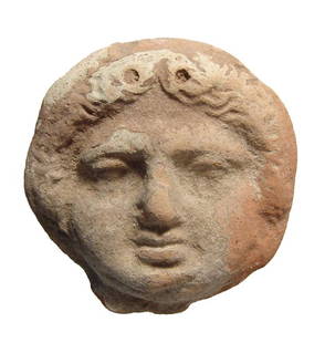 Greek terracotta roundel depicting the face of a Gorgon: A Greek terracotta roundel depicting the face of a Gorgon, c. 4th - 2nd Century BC, molded in relief with attractive features; two holes at top for suspension. 3 1/4 x 3 1/4 in (8.3 x 8.3 cm). Light