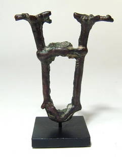 A Near Eastern bronze finial depicting two stags: A Near Eastern bronze finial depicting two stags, c. 1000 - 600 BC, from a finial the heads detailed with long tubular bodies, the legs joining to either side of the shaft hole. H: 2 4/5 in (7.2cm).