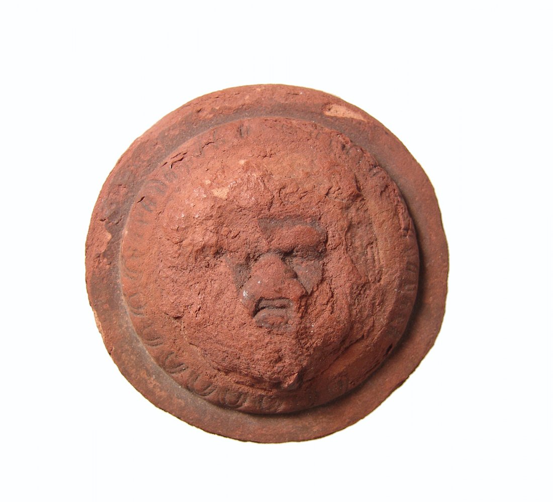 Roman-Egyptian terracotta applique depicting Bes: A Roman-Egyptian terracotta applique depicting a face of Bes, c. 1st - 3rd Century AD, the preserved area of the face nicely detailed and within an ovolo border. Dia: 3 1/4 in. (6.3 cm). Light deposit