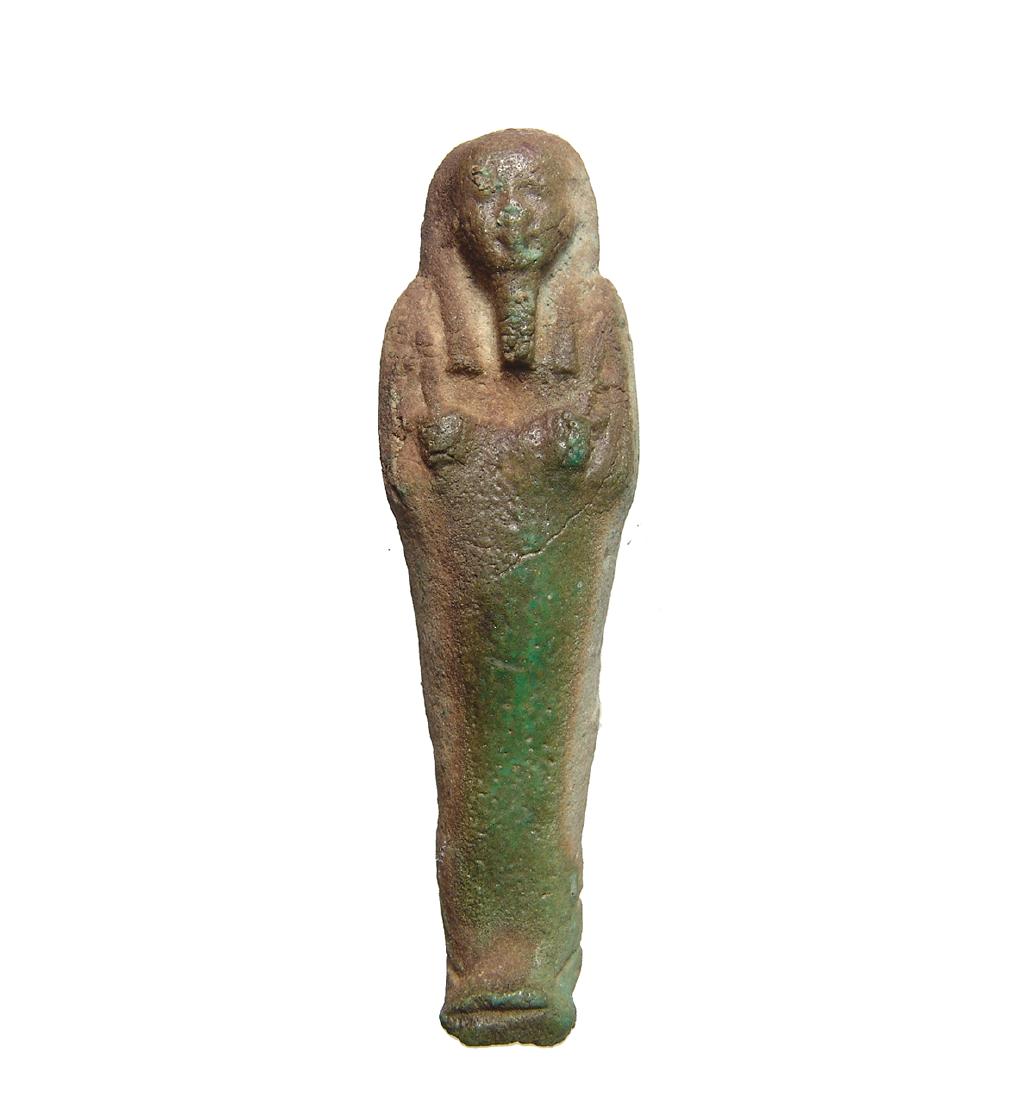 An Egyptian green glazed ushabti, Late Period: An Egyptian green glazed ushabti, Late Period, c. 664 - 332 BC, frontally molded and depicted mummiform, wearing tripartite wig with false beard, arms folded over chest and holding a pick and hoe. H: 