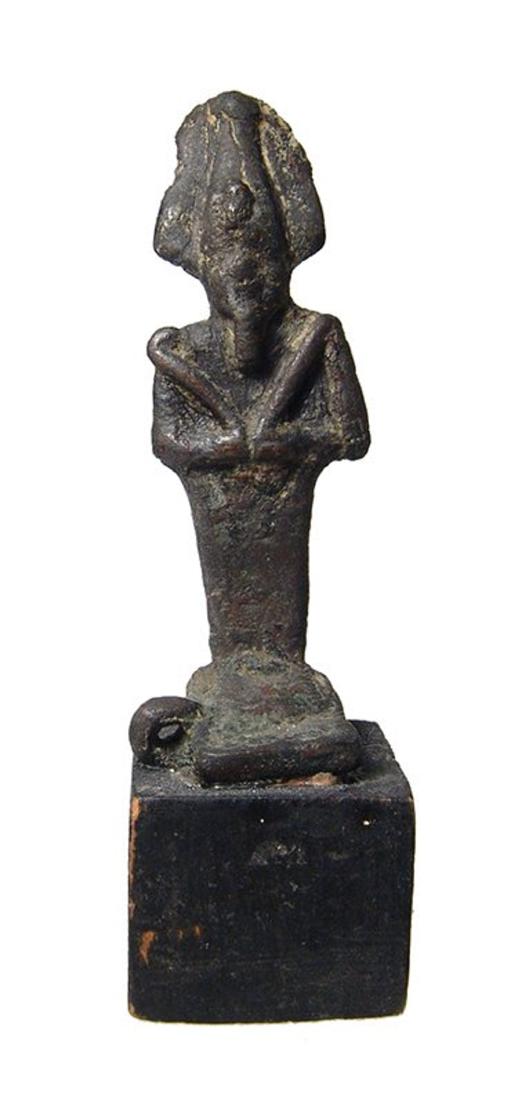 An Egyptian bronze figure of Osiris, Late Period: An Egyptian bronze figure of Osiris, Late Period, c. 664 - 332 BC, on intrinsic base and depicted mummiform, wearing Atef crown with uraeus and false beard, arms folded at chest, hands holding a crook