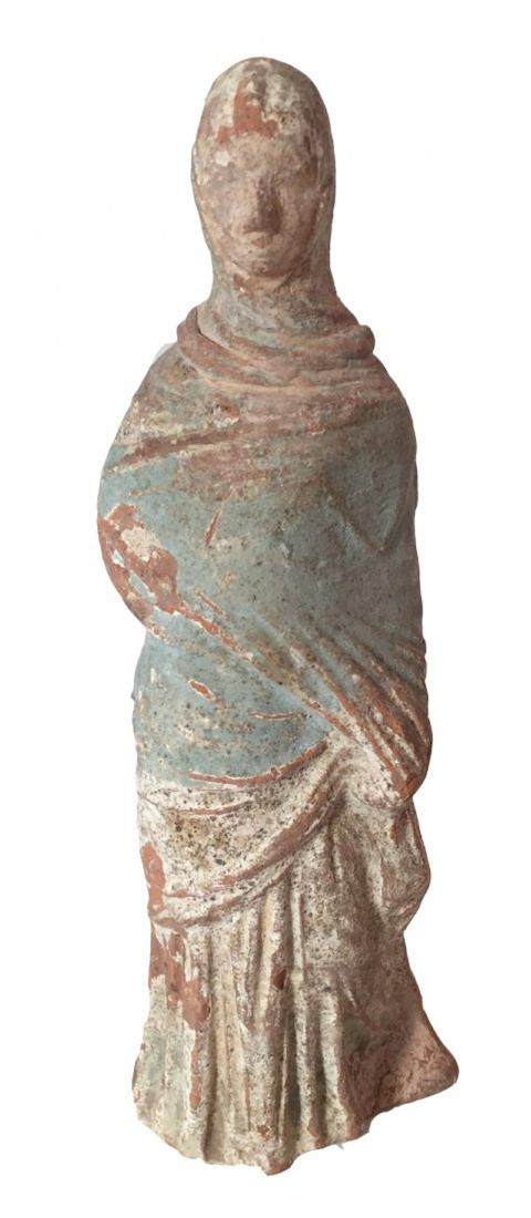 A nice Greek Tanagra figure of a bride: A nice Greek Tanagra figure of a bride, c. 4th-3rd Century BC. She stands tall with reserved features. One hand is tucked beneath her robe at the waist, with the other resting on her stomach. A vibran