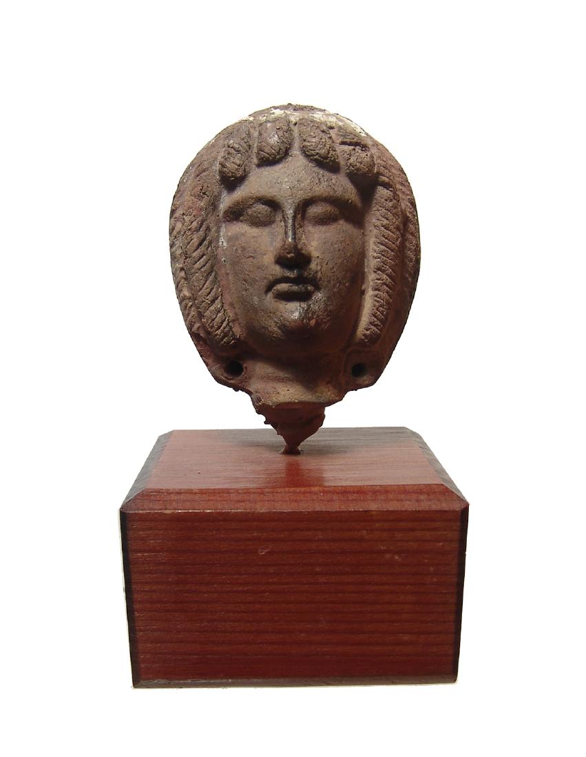 A fantastic Egyptian-Romano head of a woman: A fantastic Egyptian-Romano head of a woman, 3rd Century AD, with beautifully modeled features, her hair styled in vertical ridges with a plait drawn up the back of the head. 2 3/4 x 2 1/8 in (7 x 5.4