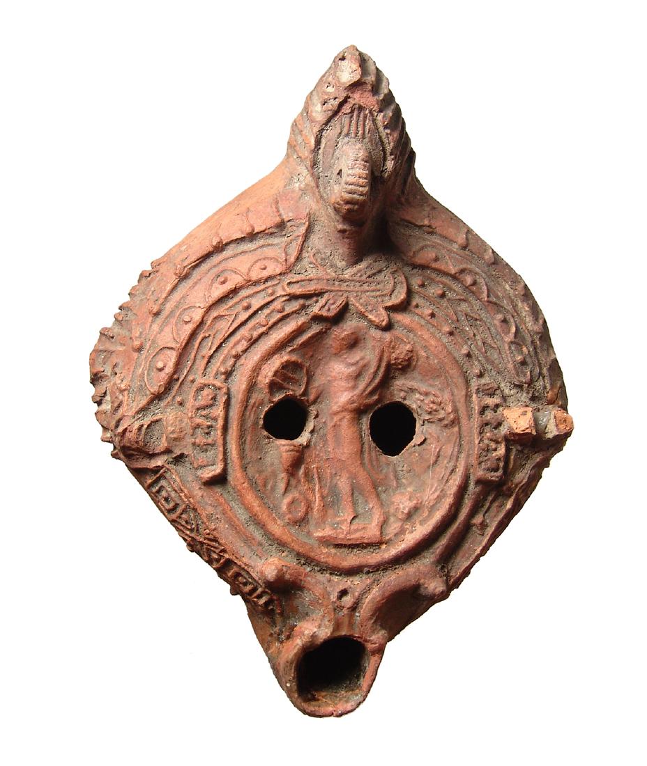 Elaborate Roman red-ware ceramic lamp, North Africa: An elaborate Roman red-ware ceramic lamp, North Africa, c. 4th - 5th Century AD, the central discus with a nude male deity, Dionysos (?) sacrificing over a tripod altar and holding a double cornucopia
