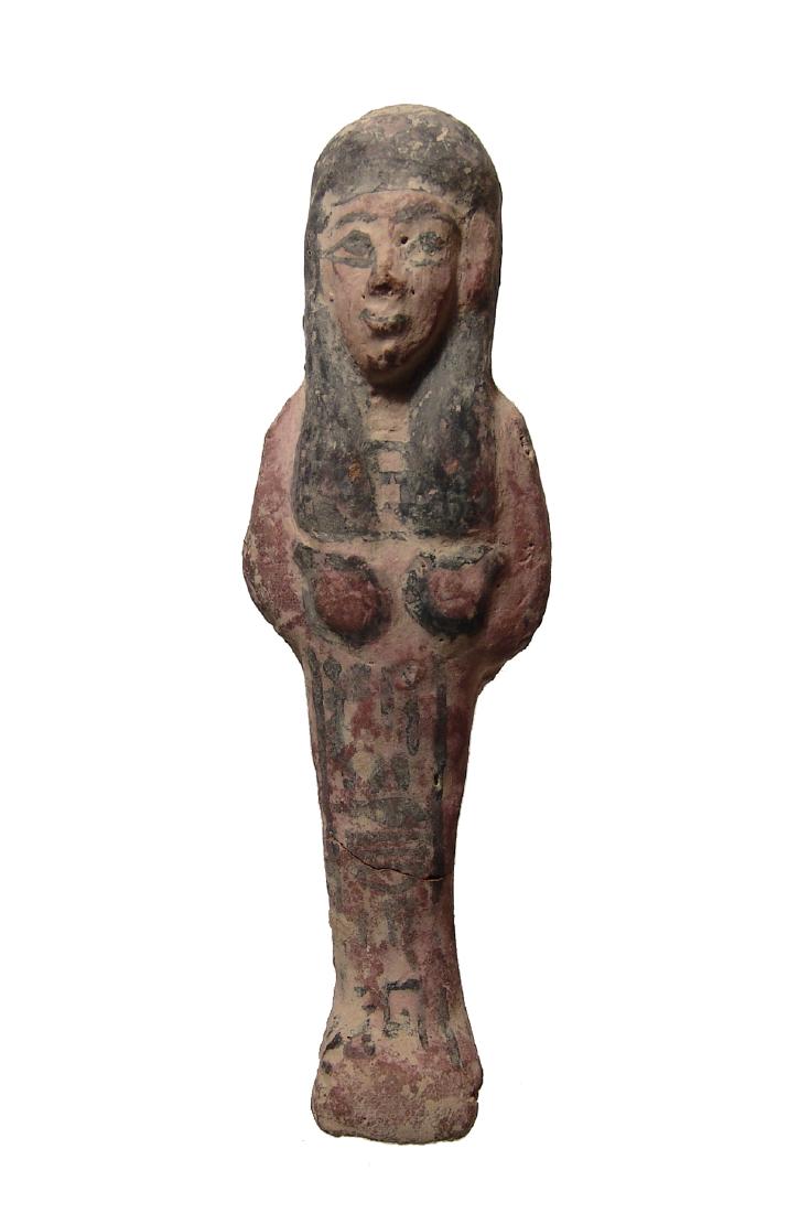 An Egyptian polychrome terracotta ushabti: An Egyptian polychrome terracotta ushabti, later New Kingdom, c. 1200 - 1075 BC, mummiform, wearing tripartite wig and broad collar, arms folded across chest, hands clutching hoes and a vertical colum