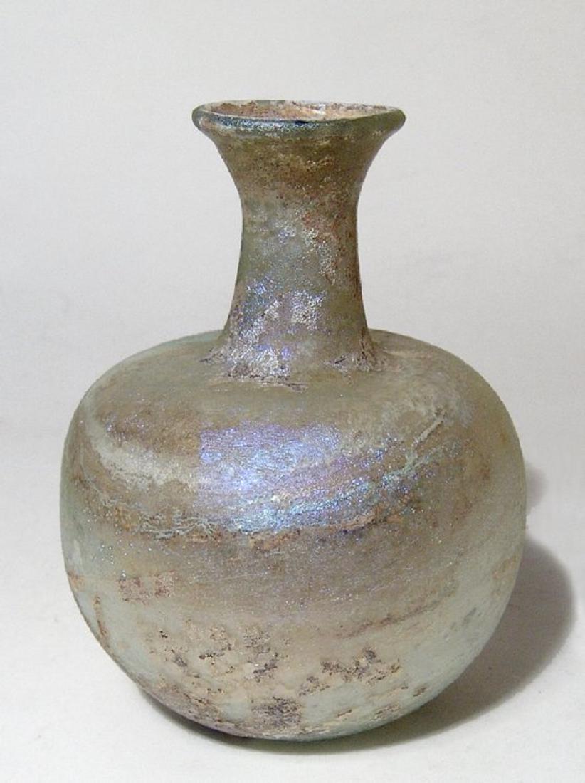 Roman pale yellow glass bottle, Eastern Mediterranean: A Roman pale yellow glass bottle, Eastern Mediterranean, 3rd - 4th Century AD, rounded body with lightly indented base, the tubular neck with widened mouth possessing an inward folded rim. H: 4 1/2 in