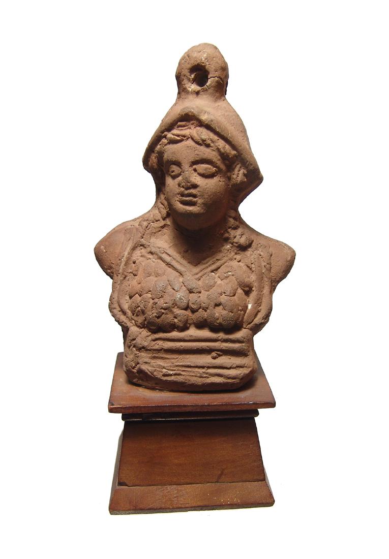 A Roman terracotta bust of Minerva, Egypt: A Roman terracotta bust of Minerva, Egypt, 1st - 2nd Century AD, atop a ridged base and wearing a helmet and aegis, her features nicely detailed with hair in curls framing her face. The bust is topped