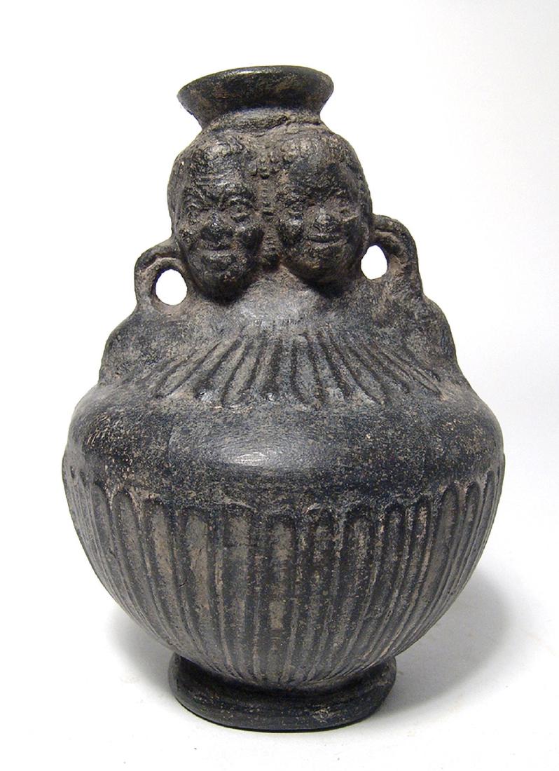 A Roman molded jug with two African heads: A Roman molded jug with two African heads, Egypt, 1st - 2nd Century AD, the body nicely decorated with vertical tongues, the shoulder as well, the spout in the form of an Ionic capital flanked by the 