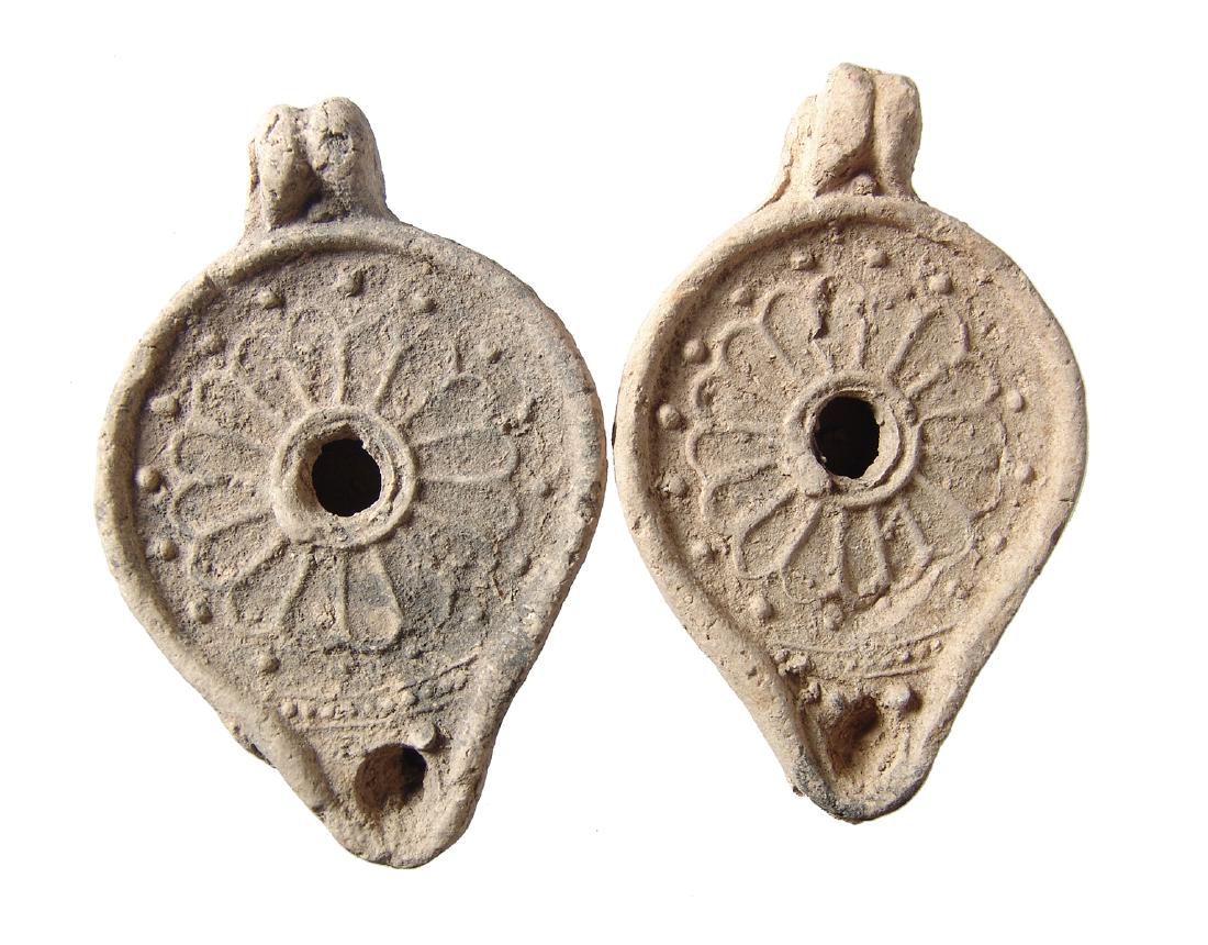 A pair of 2 matching Roman ceramic lamps, Levant: A pair of 2 matching Roman ceramic lamps, Levant, c. 2nd Century AD, mold-made, each features a central rosette around the fill-hole and beaded border setting it off from the spout. The knob handle po