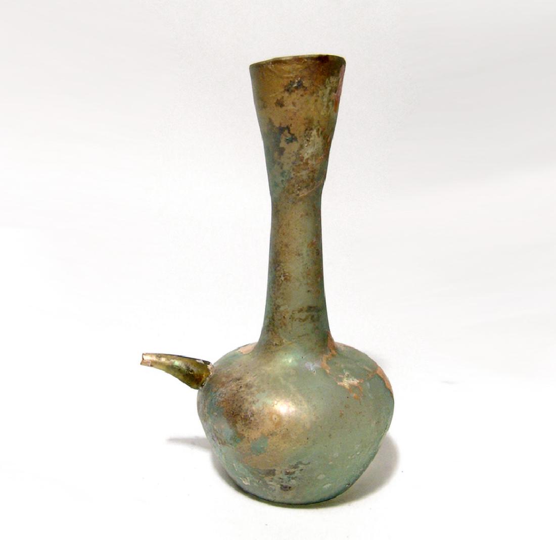 Lovely Roman pale green glass feeder flask: A Roman pale green glass feeder flask with lovely iridescence, c. 2nd - 3rd Century AD, the body bulbous with concave bottom, long neck, and flared mouth, the body with tapering spout on one side, a n