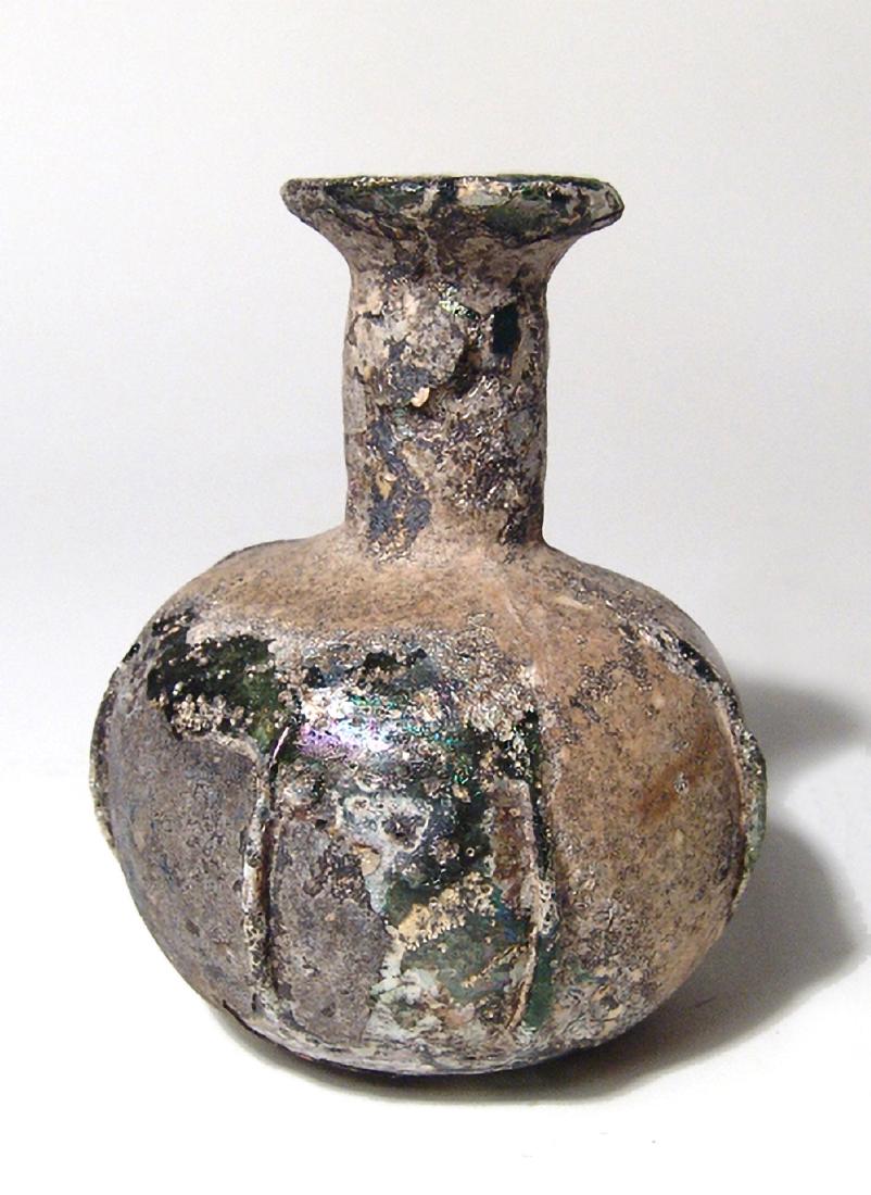 A nice Roman green glass bottle: A nice Roman green glass bottle, c. 3rd - 4th Century AD, the globular body with flattened base and vertical ridges around the outside with cylindrical neck and widely flared mouth with rounded rim. H