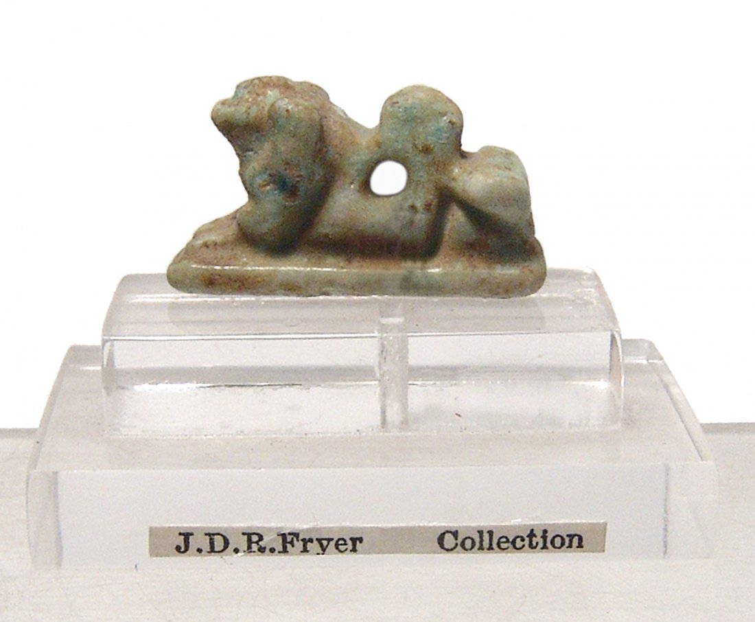 Egyptian green-glazed faience recumbent lion amulet: An Egyptian light green-glazed faience amulet of recumbent lion, Late Period, c. 664 - 30 BC, with good detail and suspension loop on back. L: 2.2 cm. With custom lucite base with collection label. Ex