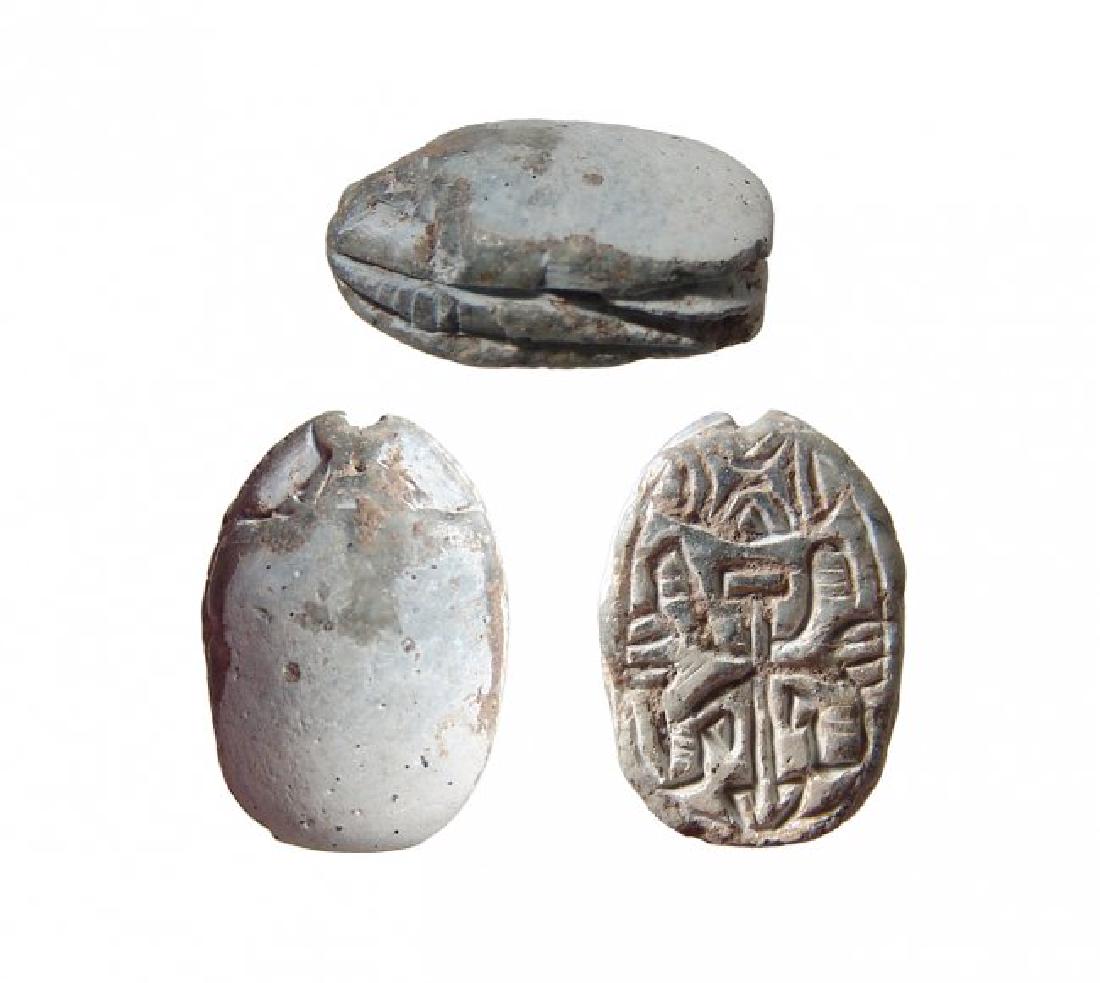 An Egyptian steatite scarab, 2nd Intermediate Period: An Egyptian steatite scarab, 2nd Intermediate Period, c. 1750 - 1570 BC, the body well-carved, on base, symmetric conjoined lotuses around a central Nefer sign, geometric motif about. 16 x 11 mm. Ligh