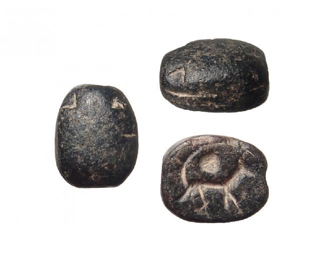 An Egyptian black steatite scarab with a jackal: An Egyptian black steatite scarab with a jackal, c. Late Period, c. 664 - 332 BC, representing Anubis, a solar disk above. 11 x 8 mm. Holed lengthwise for suspension. Ex collection of J.D.R. Fryer, UK