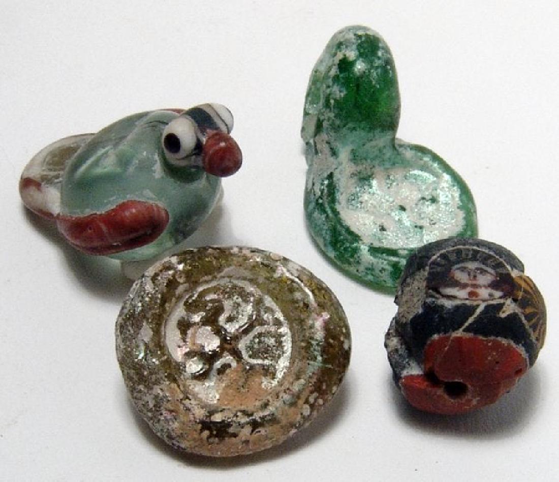A nice group of 4 small glass objects: A nice group of 4 small glass objects. Lot includes a Byzantine pale green glass pendant with cross, c. 5th - 7th Century AD, with large suspension loop, 30 x 19 mm, a Byzantine yellow glass weight or