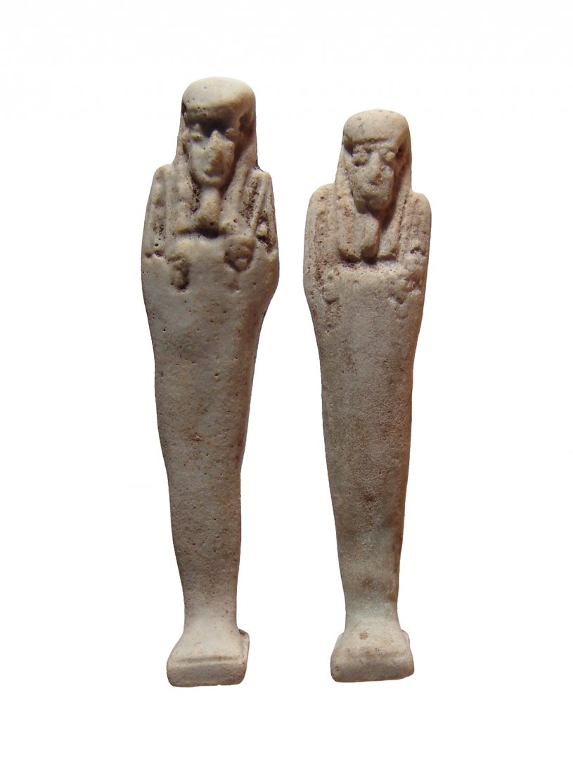 A pair of Egyptian faience ushabtis: A pair of Egyptian faience ushabtis, 30th Dynasty - Ptolemaic, c. 344 - 30 BC, each on integral base and depicted mummiform, wearing tripartite wig and false beard, arms folded across chest, hands hol