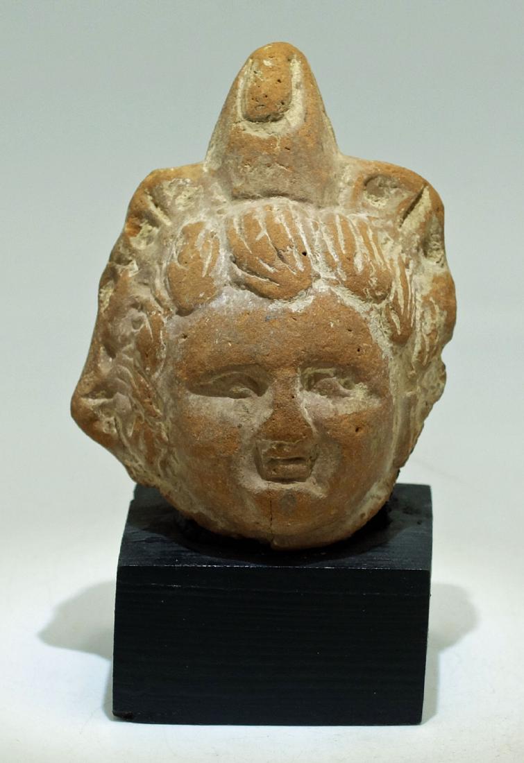 A beautifully detailed Roman-Egyptian terracotta head: A beautifully detailed Roman-Egyptian terracotta head, c. 1st - 2nd Century AD, depicting a youth adorned with a fancy spiked headdress. H: 3 1/8 in (8 cm). Nicely detailed, mounted on wood base. Ex V