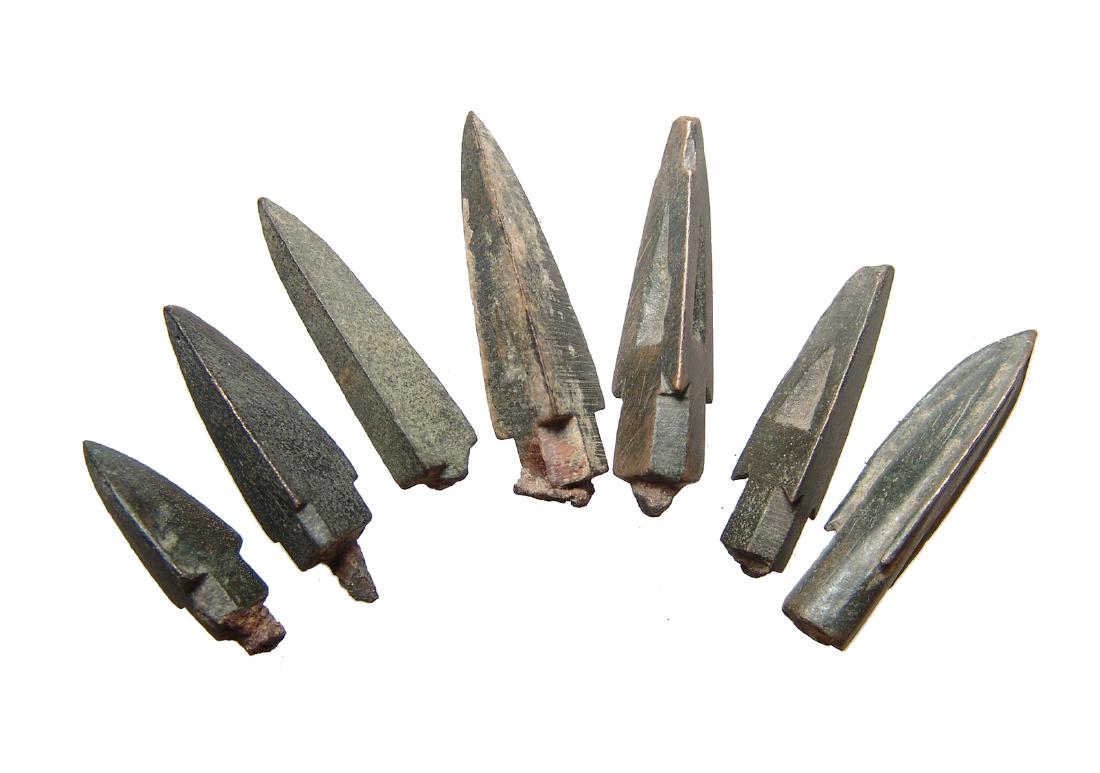 7 nice, solid Chinese bronze arrowheads, Han Dynasty: A group of 7 nice, solid Chinese bronze arrowheads, Han Dynasty, c. 206 BC - AD 200, each trilobate with a single side containing a recessed triangle, the other three sides flat. Perhaps the recessed 