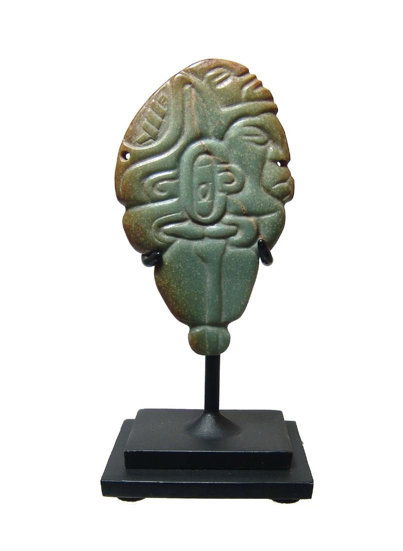 A choice Mayan jade pendant with two male heads: A choice Mayan jade pendant, c. AD 600 - 800, of exquisite manufacture featuring a male head in profile wearing earspools and an elaborate headdress, a second human head emerges above. 3 1/2 x 2 1/8 i