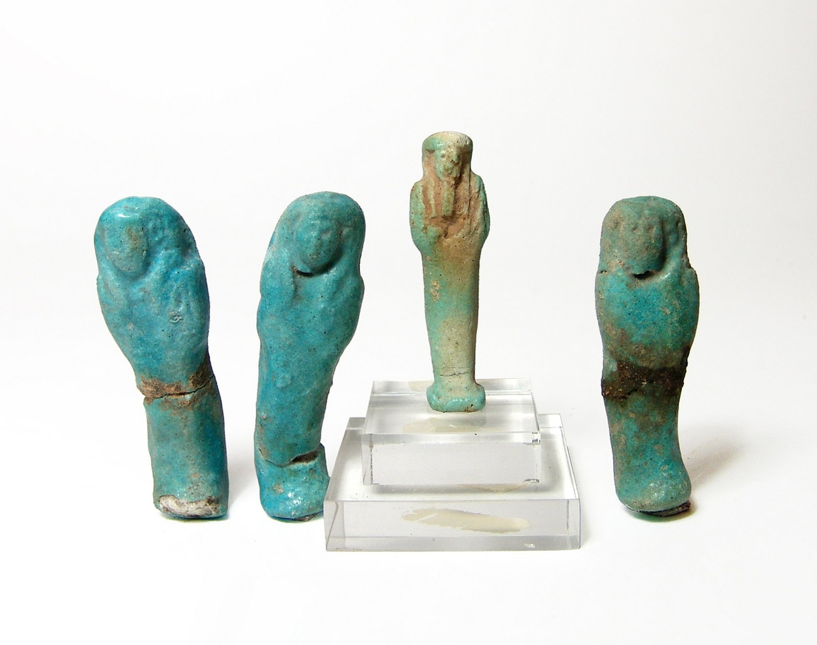 A group of 4 Egyptian blue glazed ushabtis: A group of 4 Egyptian blue glazed ushabtis, Late Period, c. 664 - 30 BC, including a cute little example on a lucite base, H: 2 in (5 cm), and three turquoise blue examples and the foot of a fourth, l