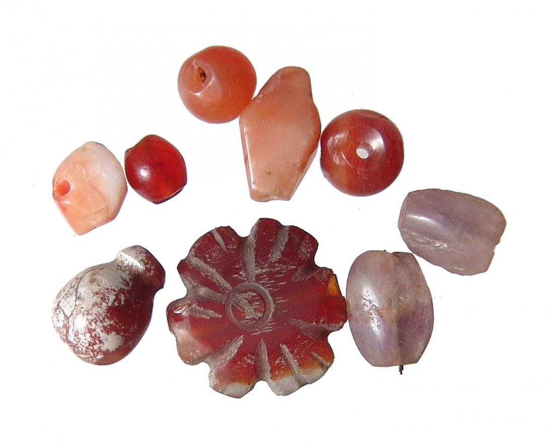 A group of Near Eastern carnelian beads: A group of Near Eastern carnelian beads, 2nd - 1st Millennium BC, in a variety of shapes and sizes and featuring a carved bead in the shape of a rosette, all drilled for suspension. Largest 18 mm in w