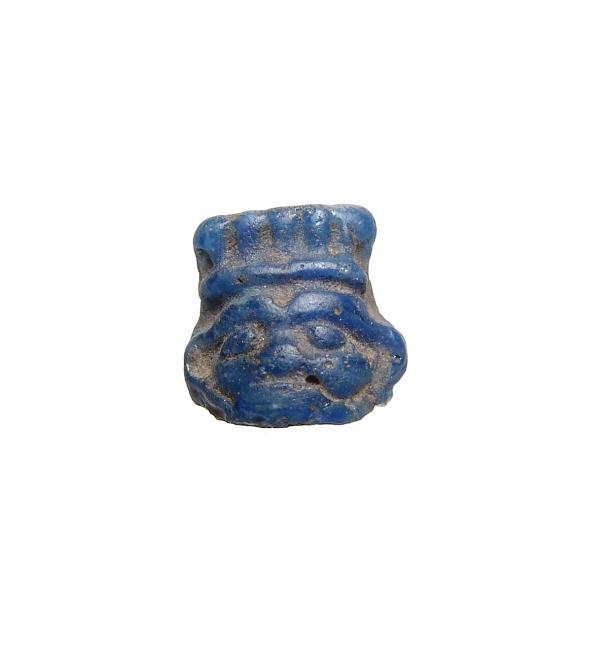 Wonderful Egyptian blue glass amulet of the head of Bes: A wonderful Egyptian blue glass amulet of the head of Bes, Late Period, c. 664 - 30 BC, with leonine features and wearing his characteristic feathered headdress. 16 x 16 mm. Ex collection of J.D.R. Fr