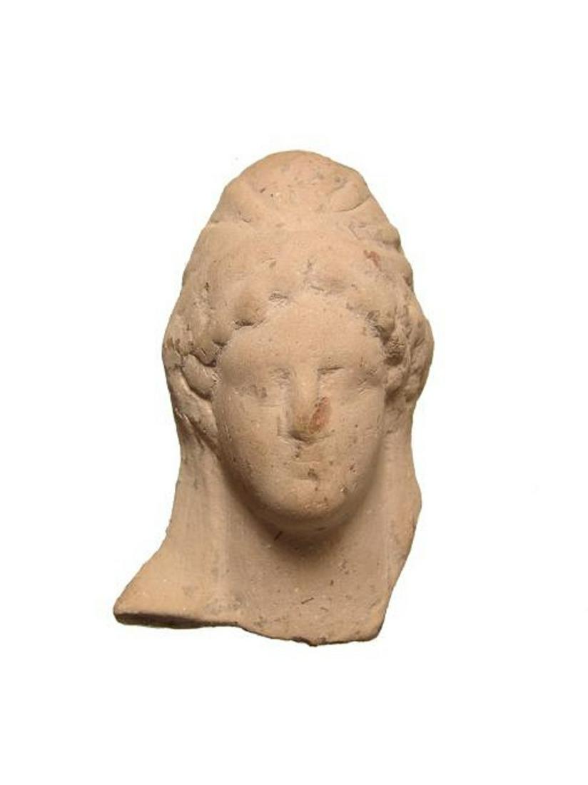 A Greek terracotta head of a woman: A Greek terracotta head of a woman, c. 5th Century BC, wearing a tall, elaborate headdress, her features attractive. 3 1/2 x 2 in (9 x 5 cm). Light deposits. Ex collection of William Major Tedder.