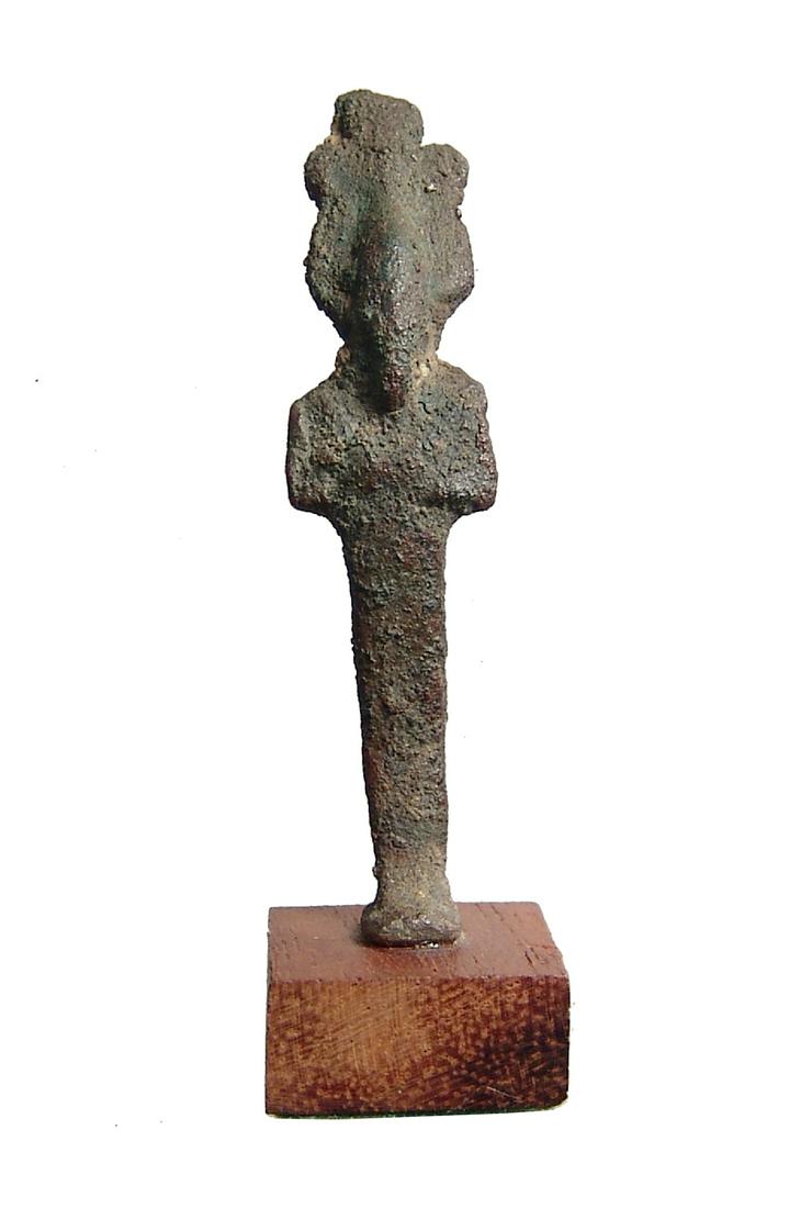 A cute Egyptian bronze votive figure of Osiris: A cute Egyptian bronze votive figure of Osiris, Late Period, c. 664 - 30 BC, wearing large Atef crown and holding crook and flail, suspension loop at back. H: 2 in(5 cm). Mounted on old wood base. Ex 